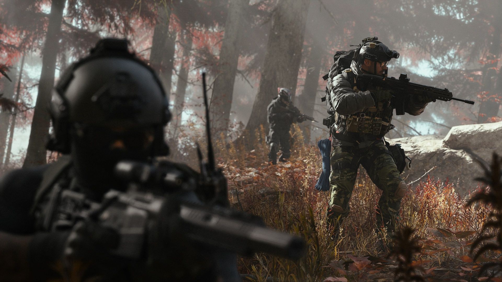 Three soldiers wade through brush between trees and a rock outcropping, rifle barrels extended in front of them, ready for action.