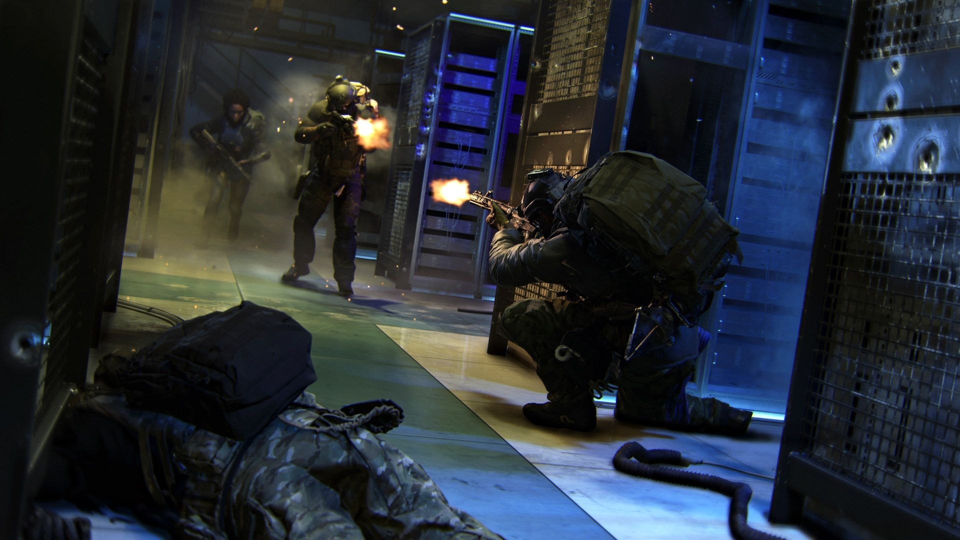 One fallen soldier lies on the floor, and another is kneeling and firing toward advancing soldiers, in what looks like a server room.